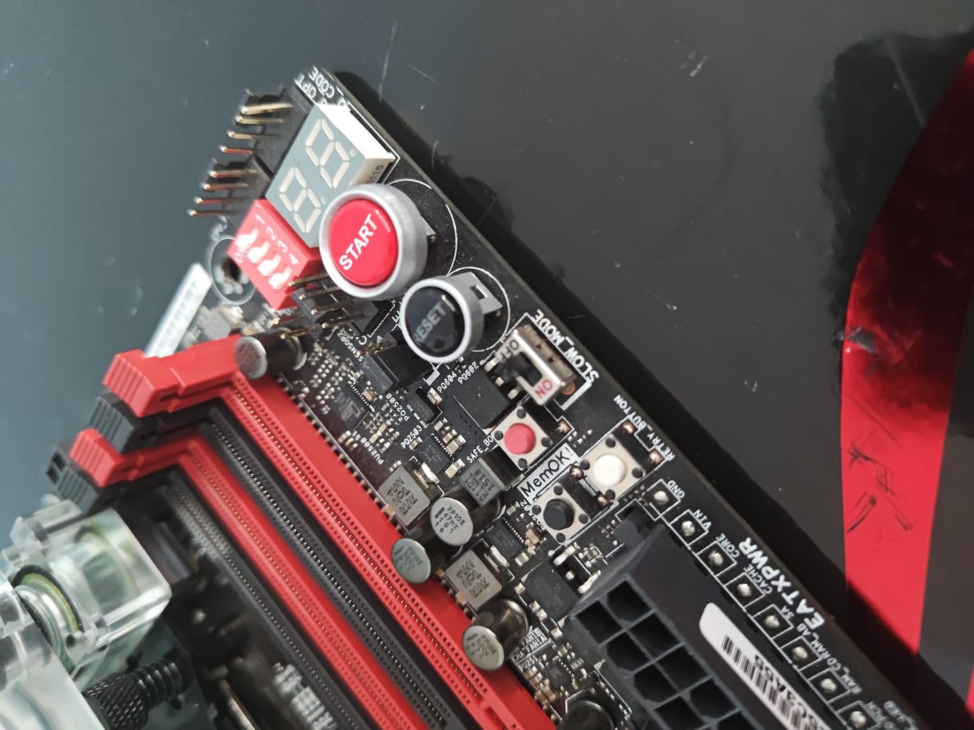 Rampage V Extreme onboard control cluster — POST code display, red START button, RESET, SLOW_MODE switch, MemOK!, and Safe Boot buttons visible along top edge